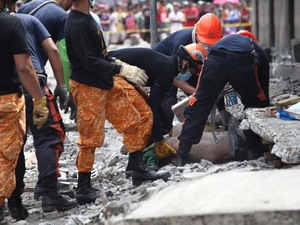Nhân viên cứu hộ đang đưa những thi thể ra khỏi đống đổ nát.